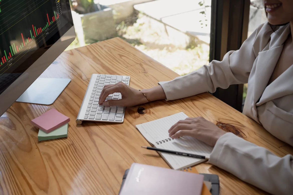 This image shows a Data Analyst working on graphs, and trends on a table with a laptop and sticky notes.